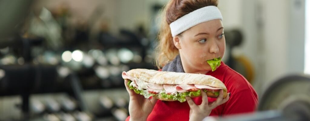 woman eating ham roll in the gym